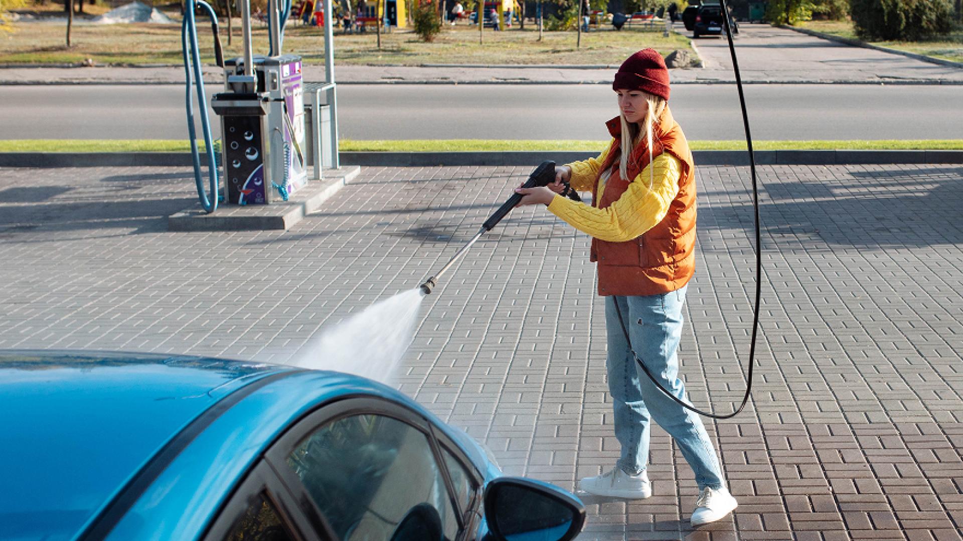 Woman washing a car with a pressure washer.