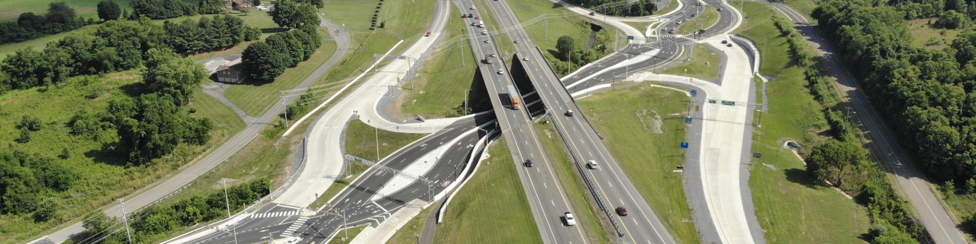 An aerial view of a highway intersection with cars on highways. 
