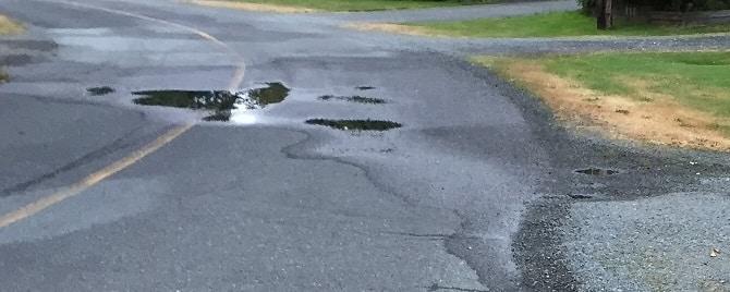 A cluster of puddles in the middle of a road.
